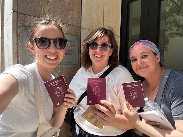 Danette, Rachel and Emma show off their new passports, after qualifying for Luxembourg citizenship